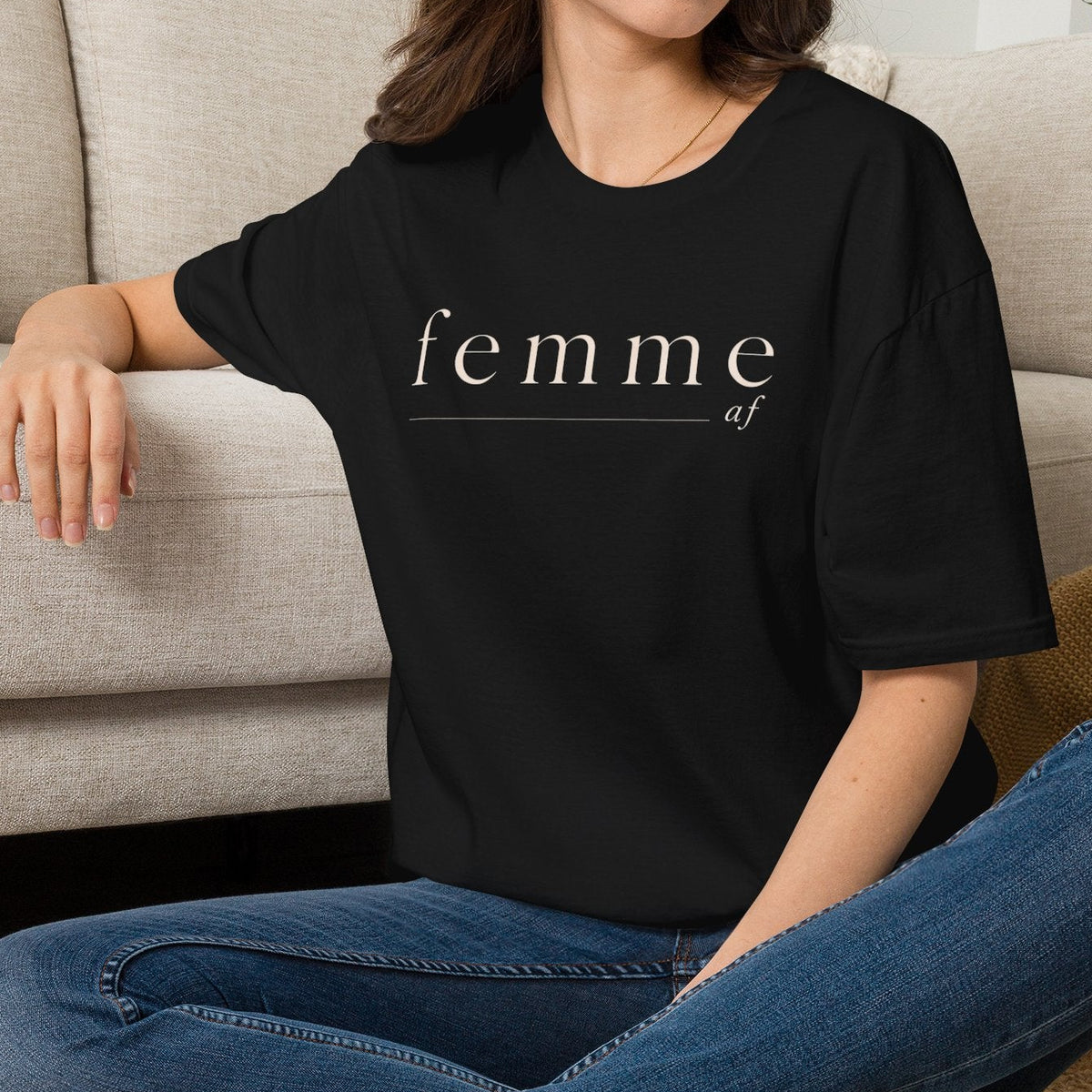 Person wearing a black t-shirt with 'EmotionLess' text, sitting on the floor in a living room.