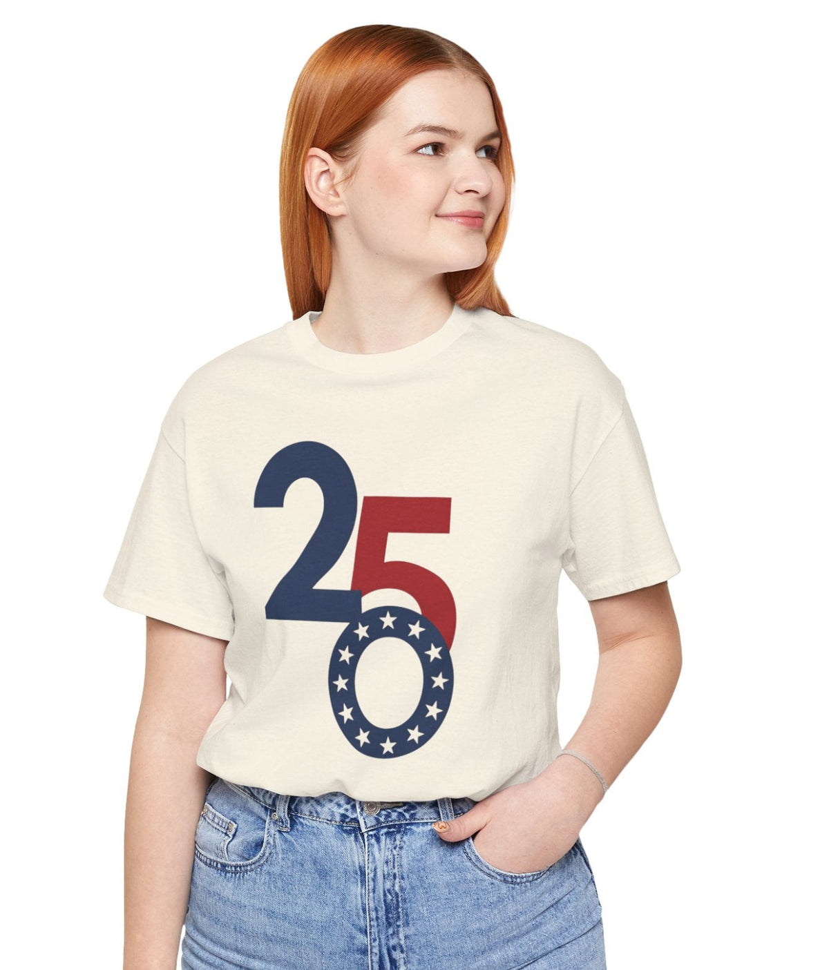A woman with red hair wearing a cream-colored t-shirt with a red and navy blue '250' graphic on the front, paired with light blue jeans, against a plain white background.
