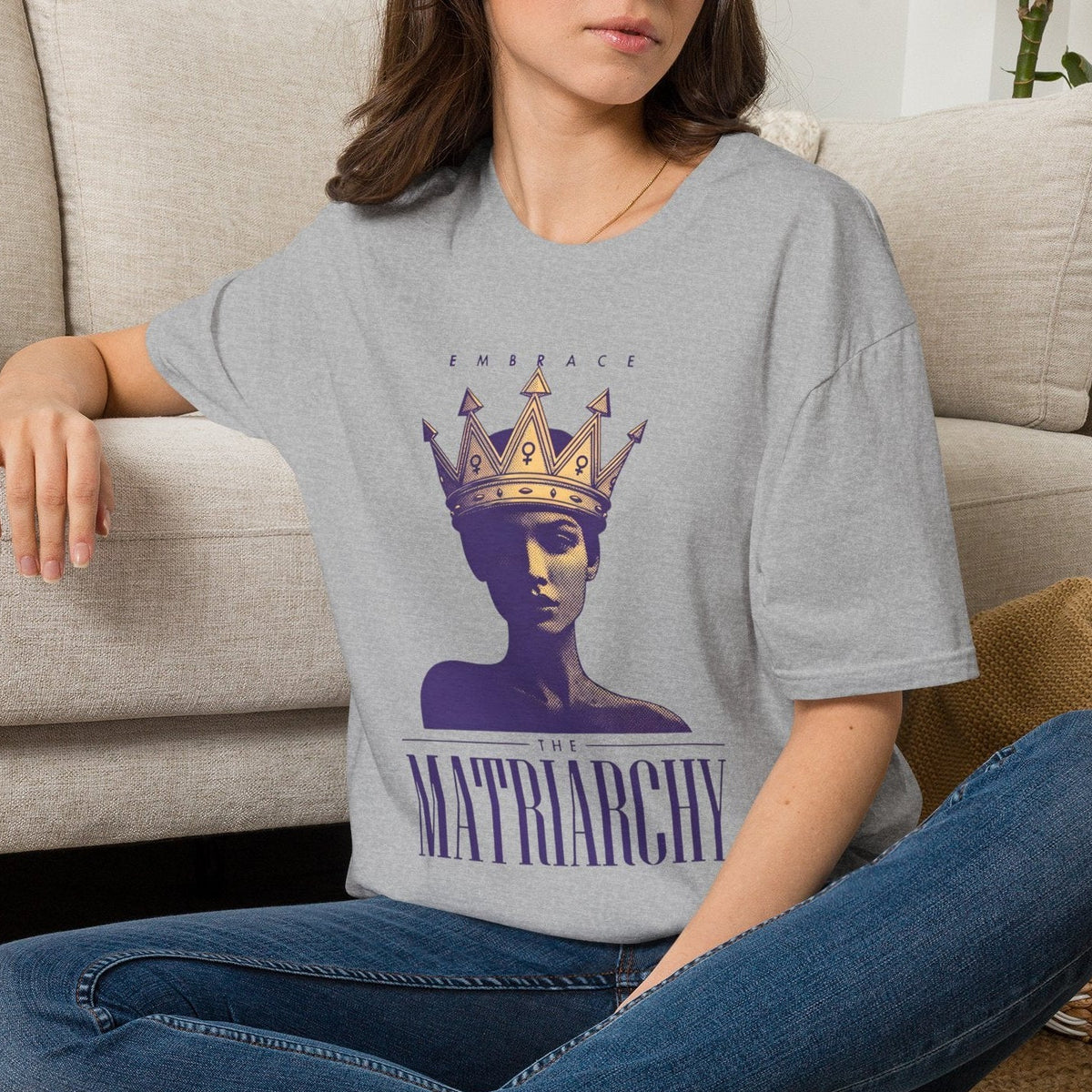 Person sitting on a couch wearing a gray t-shirt with a graphic design.